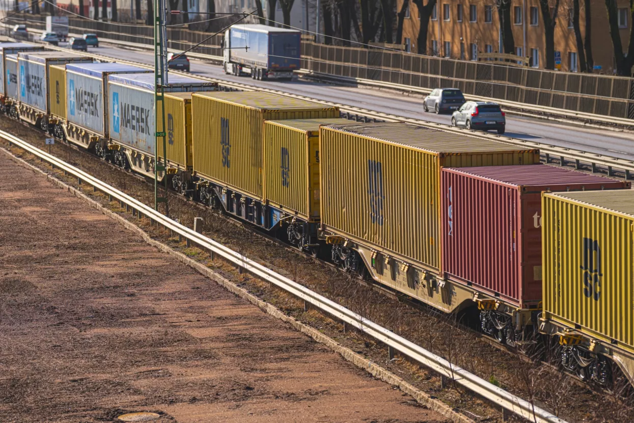 Gothenburg, Sweden - March 01 2026Freight container train transporting cargo alongside urban highway at sunset