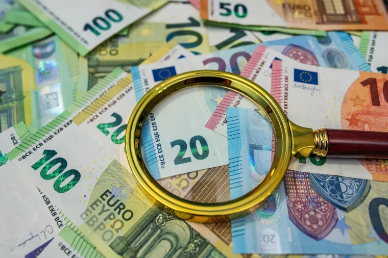Magnifying glass on euro bills, finance analysis, audit, banking and business investigation concept
